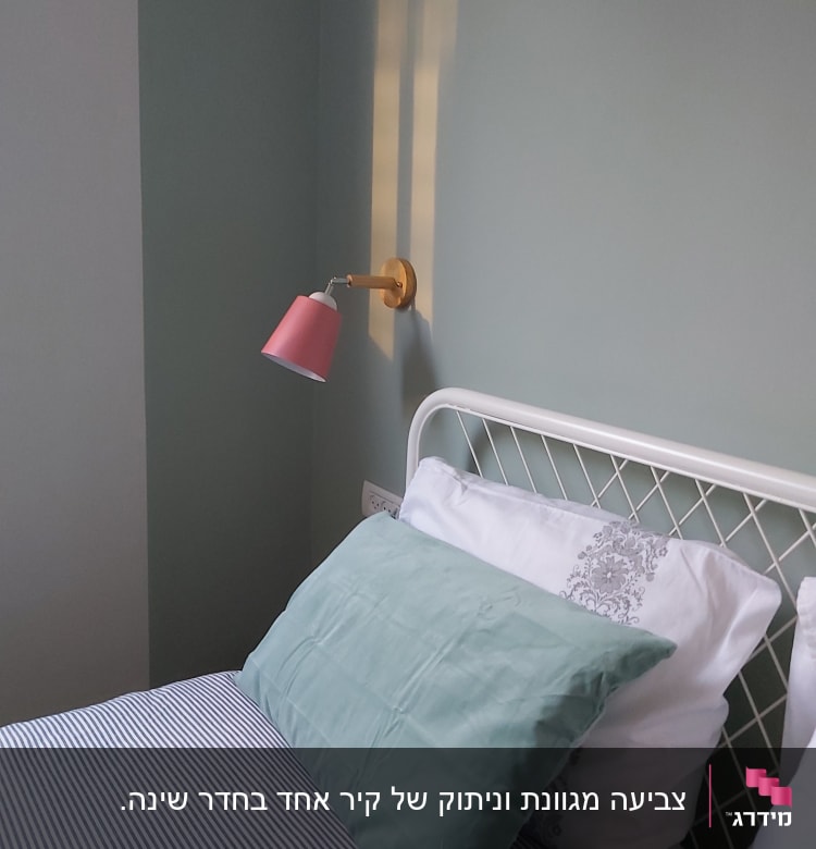 קיר צבוע בגוון ירוק עם מנורת קיר ורודה